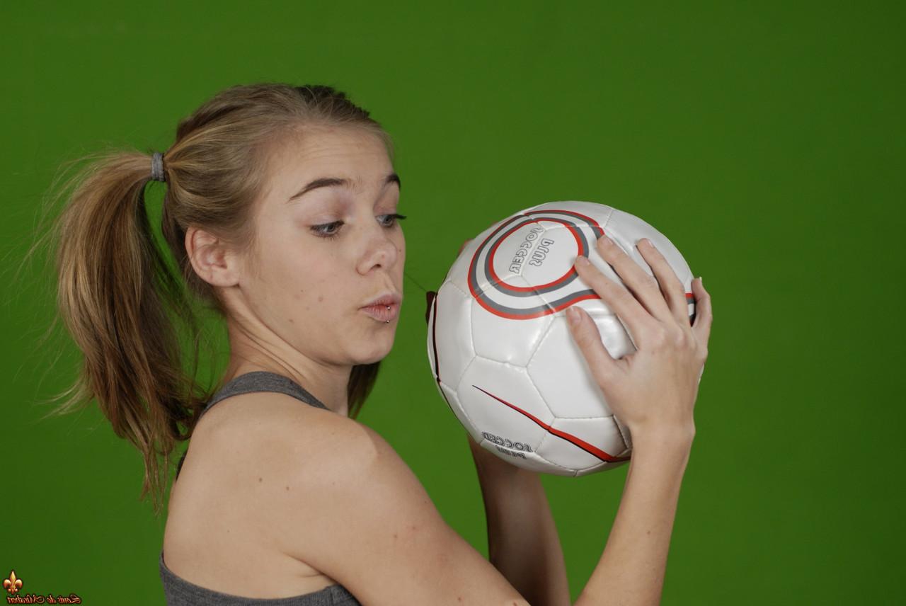 16P Das zierliche Mädchen Kelly entblößt ihre Brust, während sie einen Fußball hält
