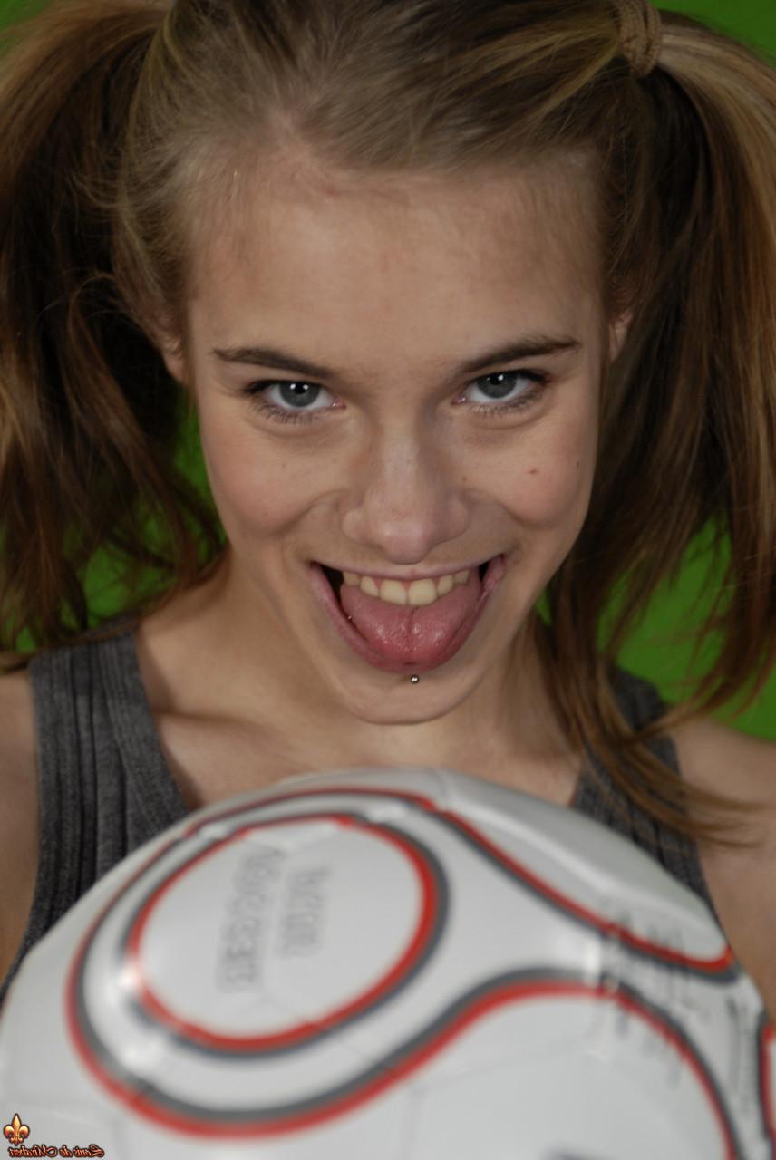 16P Das zierliche Mädchen Kelly entblößt ihre Brust, während sie einen Fußball hält