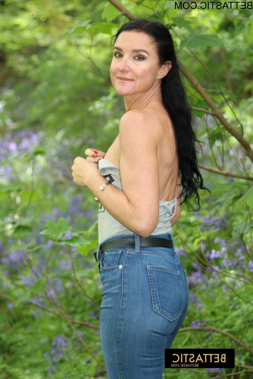 15P A linda morena Bettastic posa ao ar livre com uma blusa sem alças e jeans justos