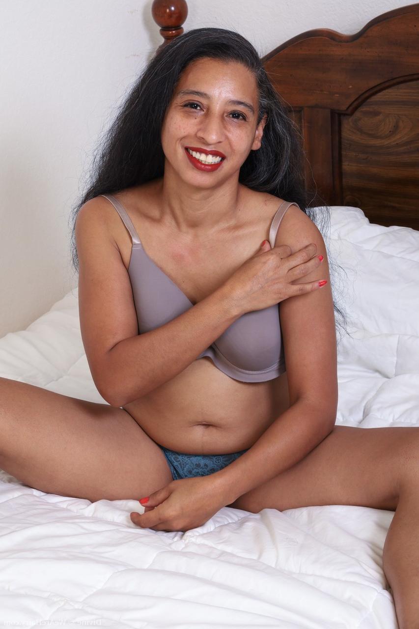 20P La amateur de pelo largo Divine hace alarde de sus pequeñas tetas y su castor tupido en una cama