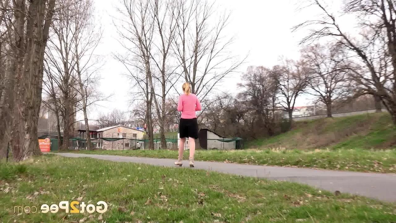 15P Mädchen mit erdbeerblonden Haaren zieht bei einer Mutprobe ihren Rock hoch, um auf dem Rasen zu pinkeln
