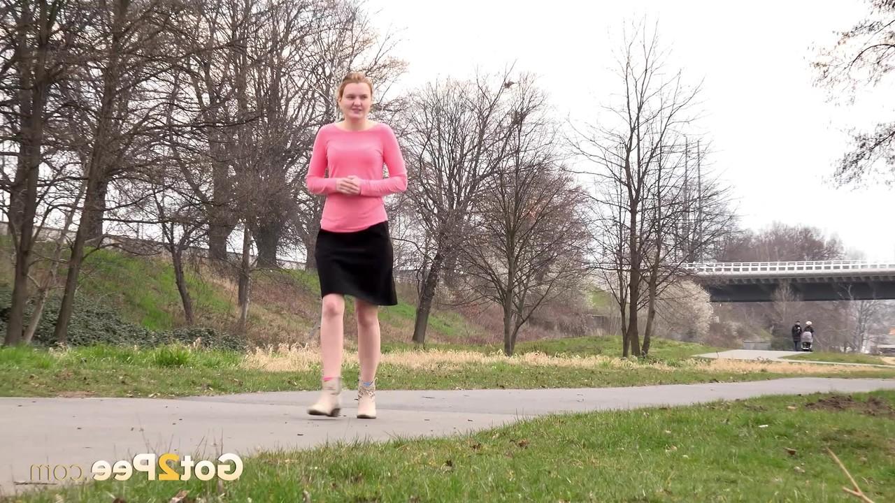 15P Mädchen mit erdbeerblonden Haaren zieht bei einer Mutprobe ihren Rock hoch, um auf dem Rasen zu pinkeln