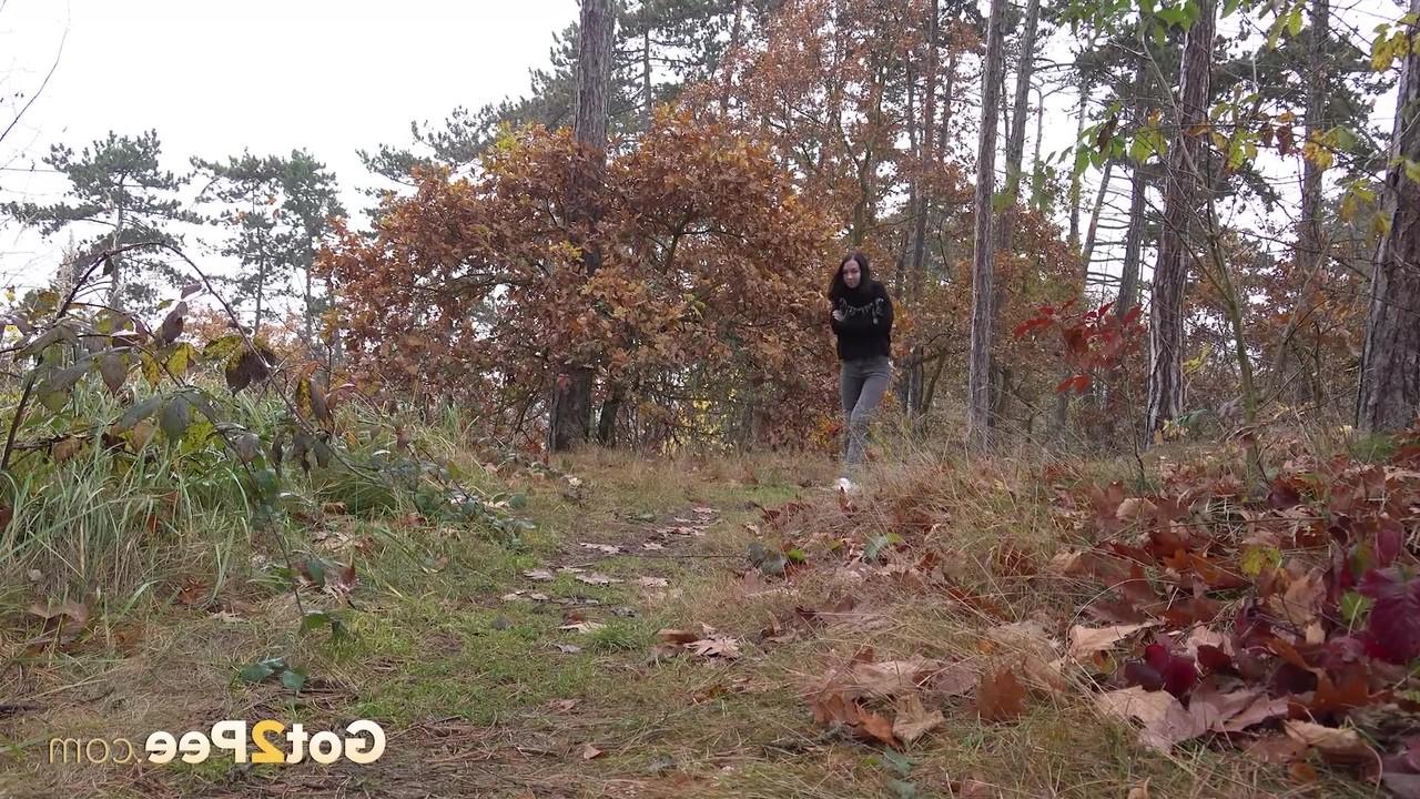14P Bekleidetes Mädchen zieht ihre Hose herunter, um auf einem Waldweg zu pinkeln