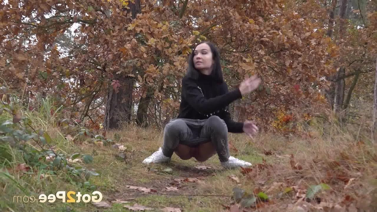 14P Bekleidetes Mädchen zieht ihre Hose herunter, um auf einem Waldweg zu pinkeln