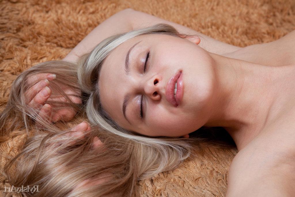 16P La jeune blonde Luciana pose nue sur un tapis.