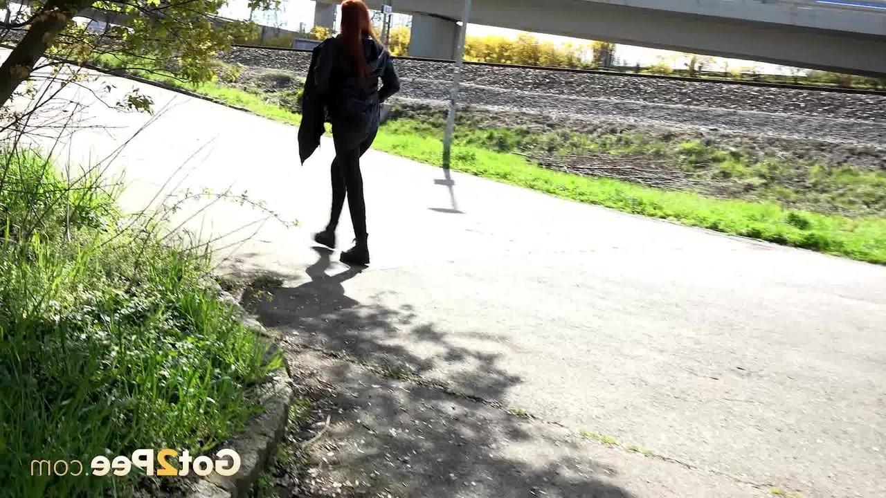 15P La joven pelirroja Katy Rose orina en una carretera pavimentada durante el día