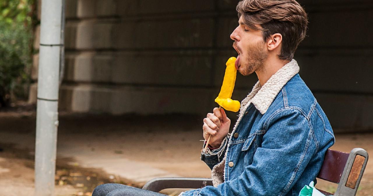 12P Gay brunette Victor A erotically sucks a sex toy lollipop on a public bench