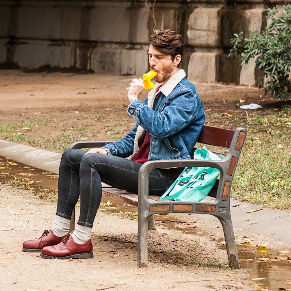 12P Gay brunette Victor A erotically sucks a sex toy lollipop on a public bench