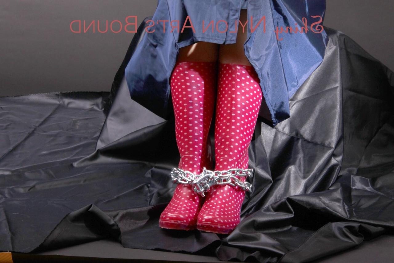 16P Caucasian female is restrained and gagged in a raincoat and rubber boots