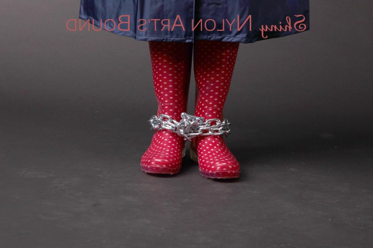 16P Caucasian female is restrained and gagged in a raincoat and rubber boots