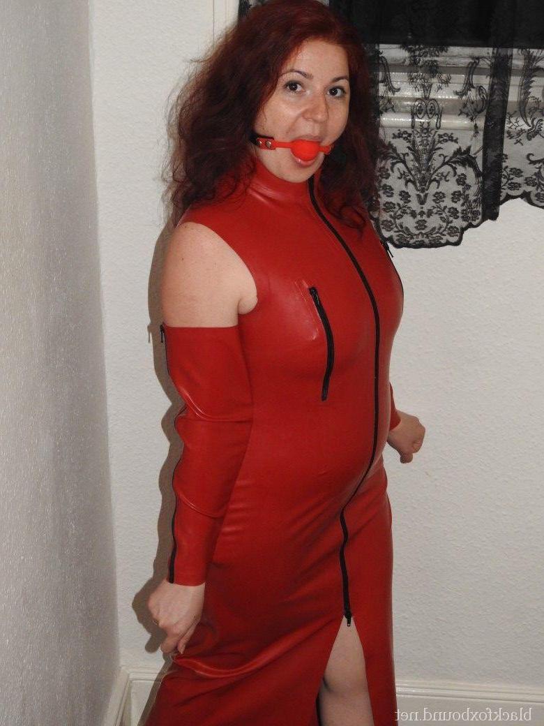 16P Ruiva natural ostenta uma mordaça de bola enquanto usa um vestido longo de látex e salto alto