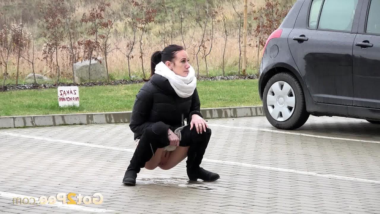 15P A garota sozinha Eveline Neill se agacha para mijar em um estacionamento com roupas de inverno
