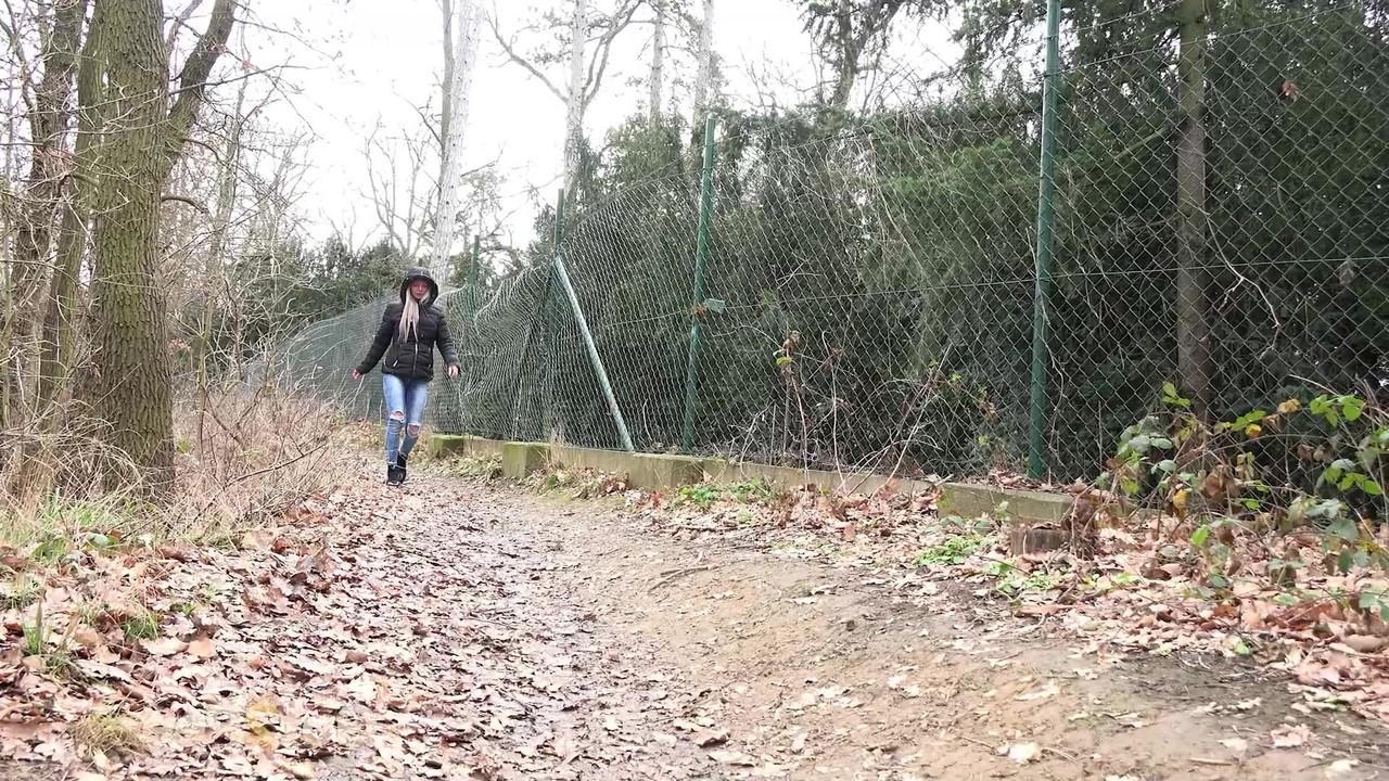 15P A garota branca Lilly puxa jeans rasgados para fazer xixi nas folhas ao lado de um caminho