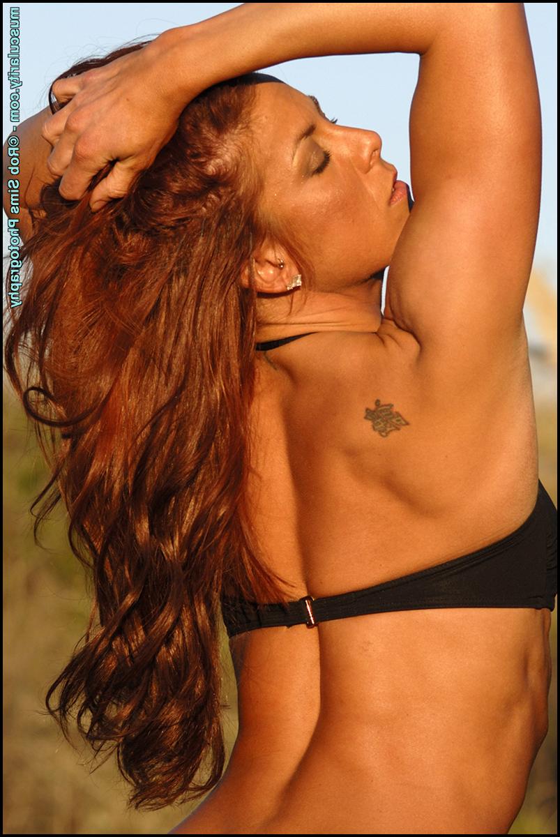 15P Erin Reid, bodybuilder rousse, pose en extérieur dans un bikini noir.