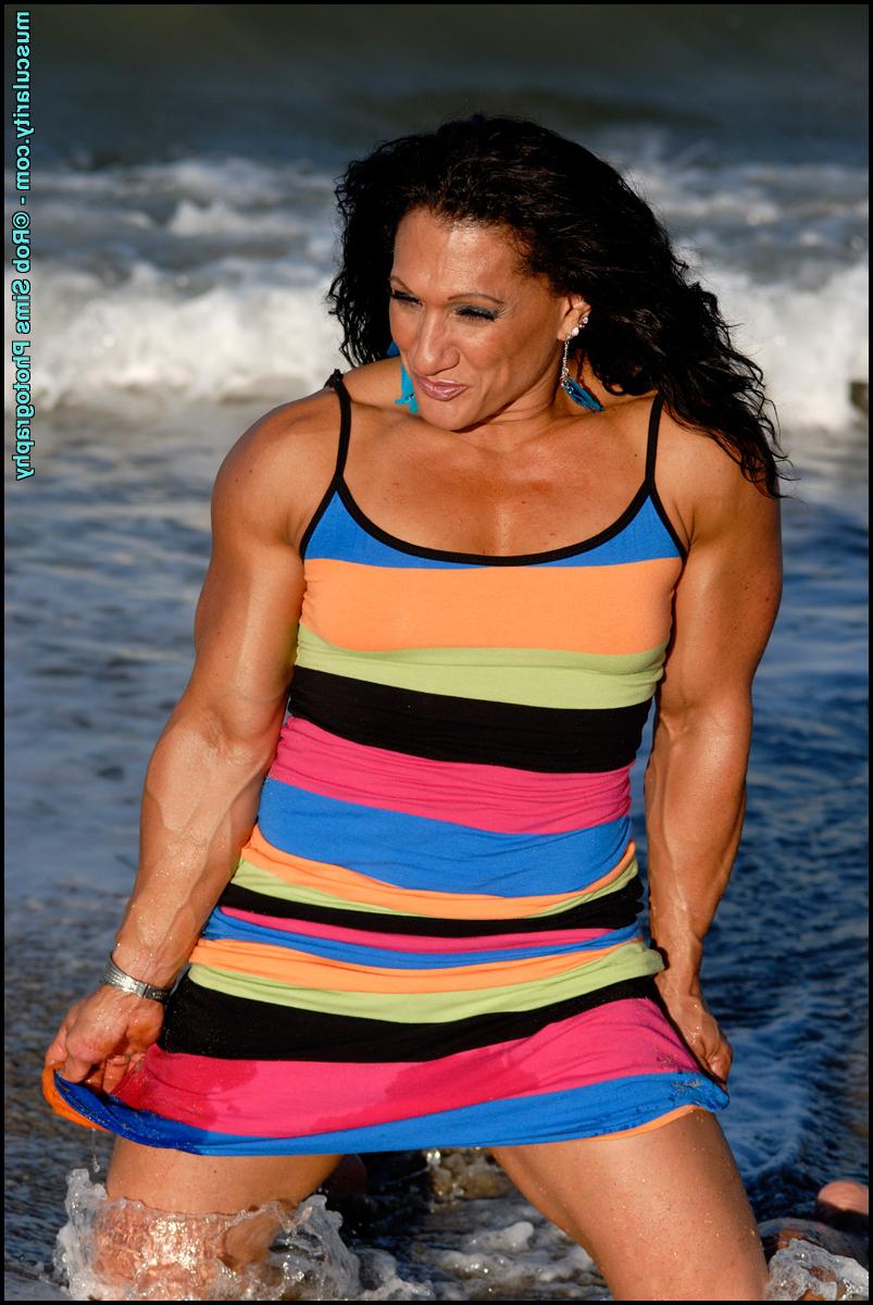 15P La culturista morena tonia moore flexiona sus músculos en la playa con un vestido