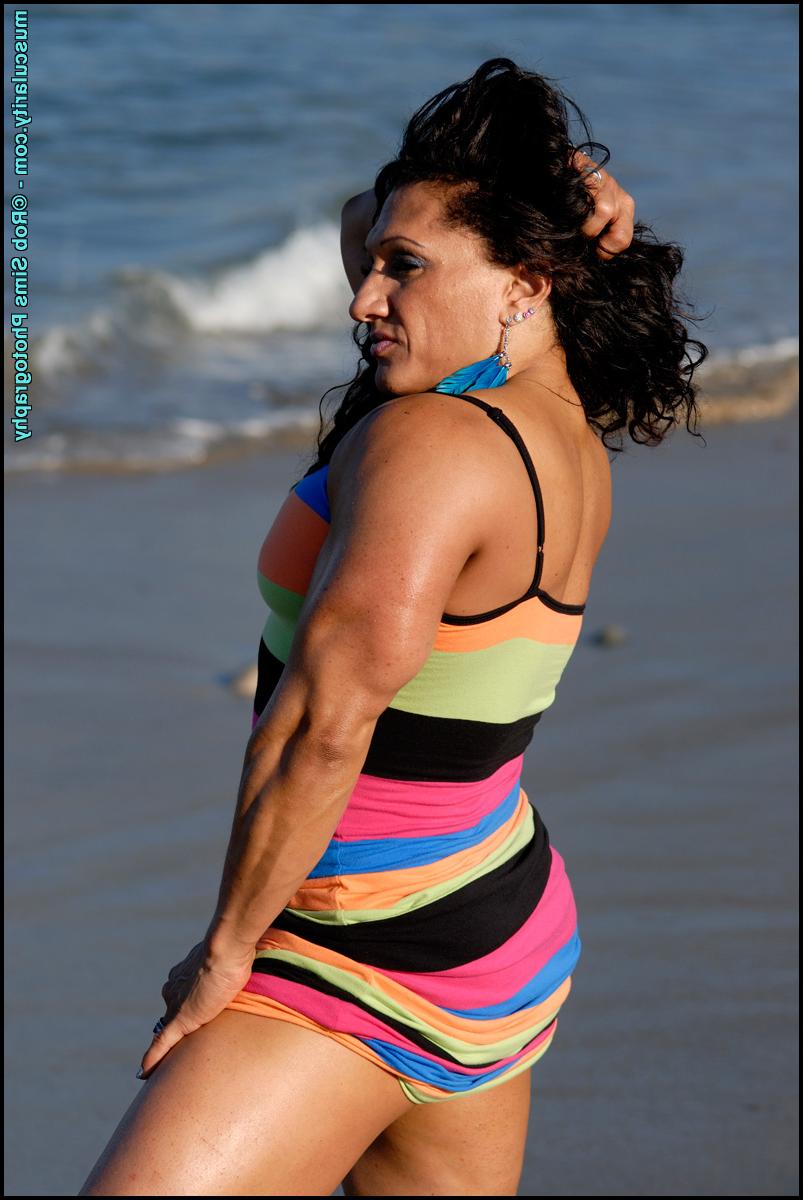 15P La culturista morena tonia moore flexiona sus músculos en la playa con un vestido