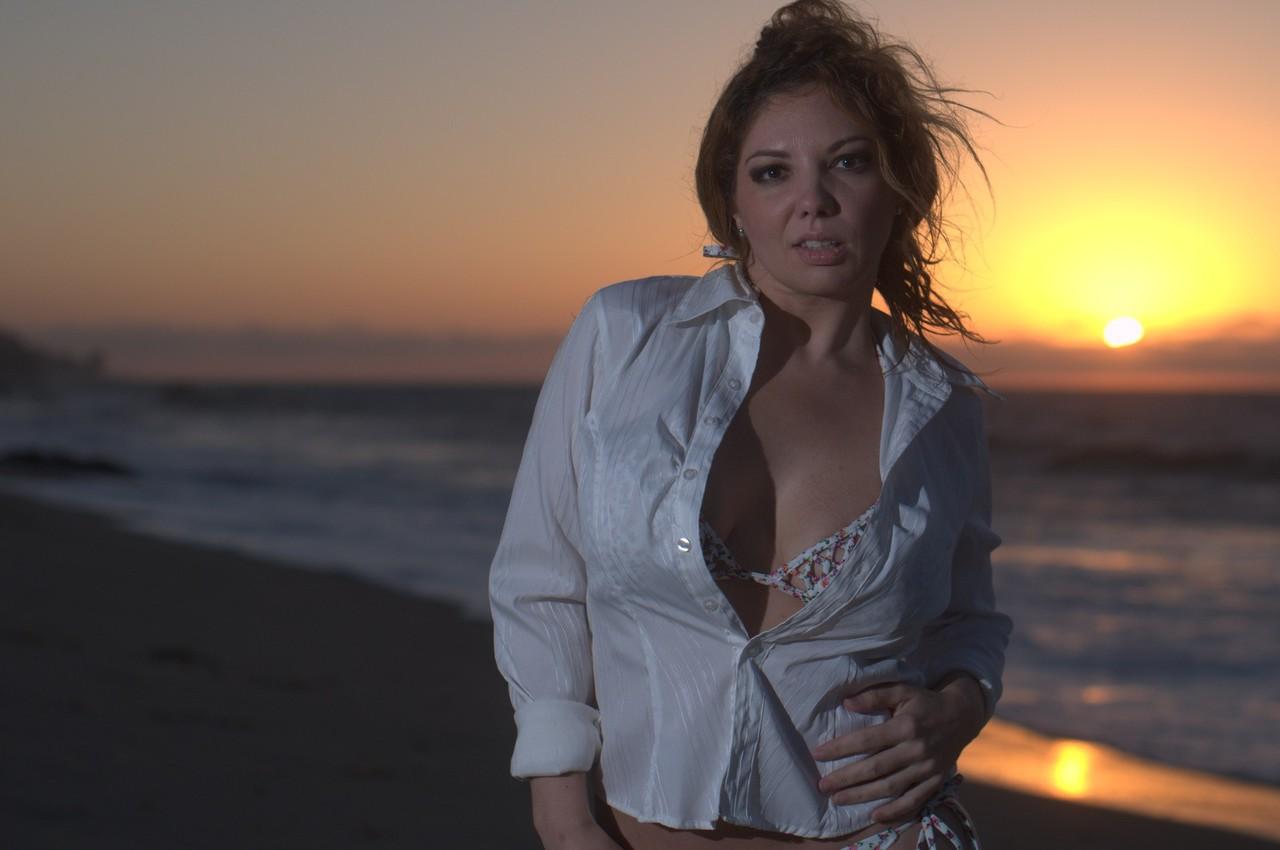 17P Mulher de meia idade Kiki Daire modela blusa e biquíni em uma praia ao pôr do sol