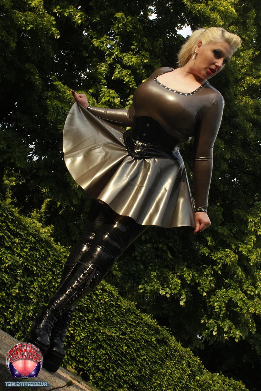 16P Une blonde pose dans des vêtements en latex et des bottes en cuir dans un jardin