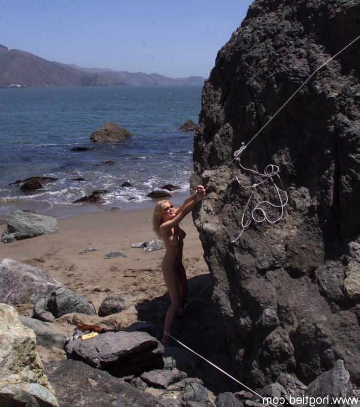 17P A escrava madura nua Sadie Belle fica amarrada a uma pedra enorme na praia