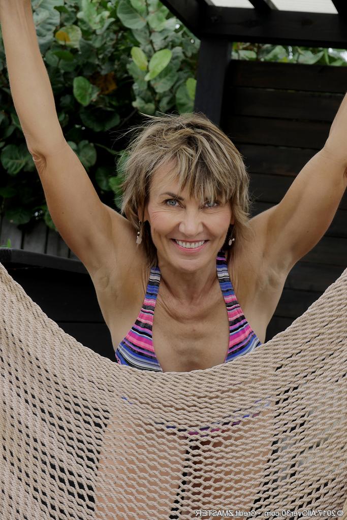15P La madura Lillian Tesh se mete los dedos en el coño en una hamaca después de quitarse el bikini
