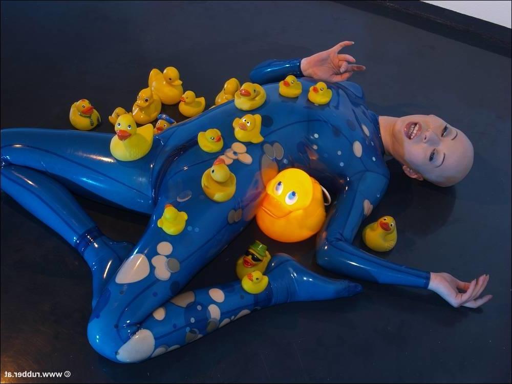 16P Bald female models rubber attire during a solo engagement