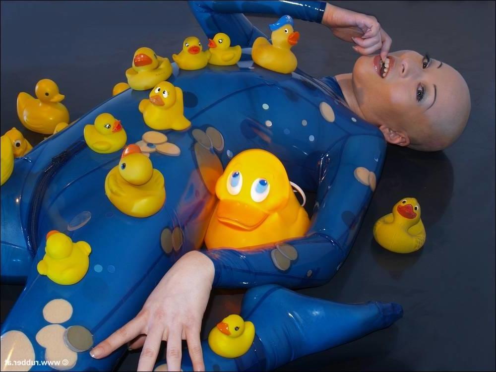 16P Bald female models rubber attire during a solo engagement