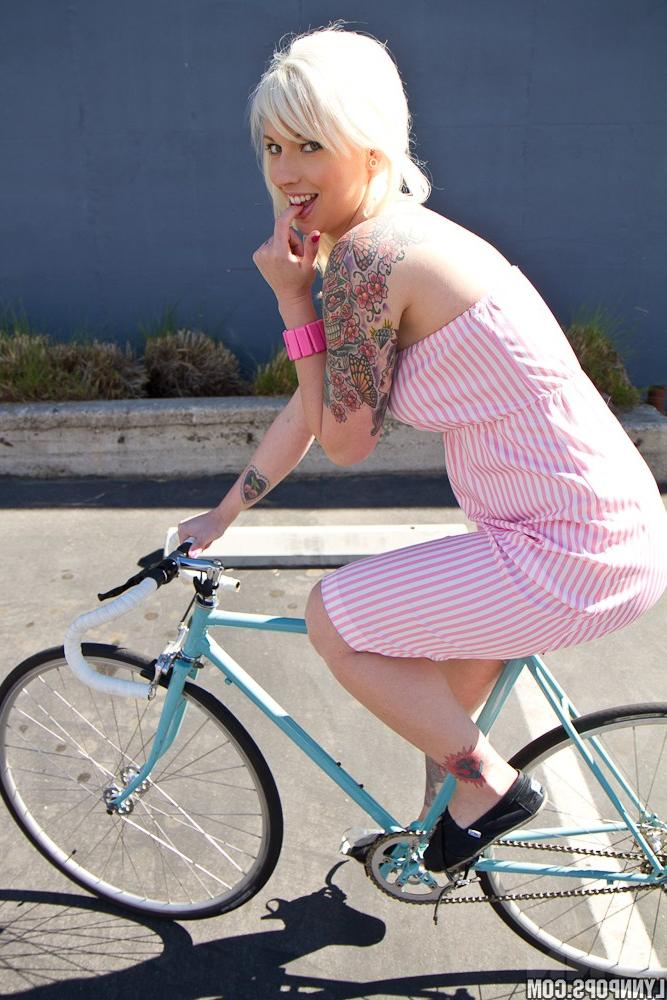 15P A amadora loira platinada Lynn Pops mostra seus peitos em cima de sua bicicleta