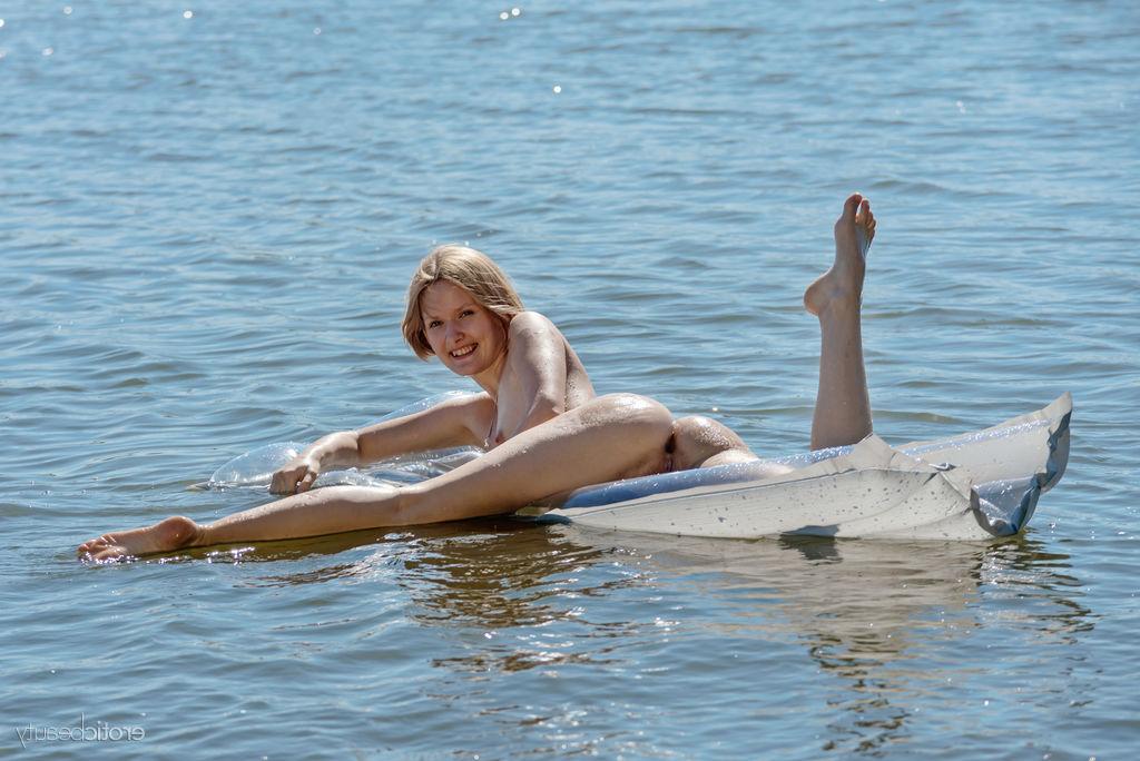 16P La jeune blonde Mak pose totalement nue sur un matelas pneumatique dans l'eau.