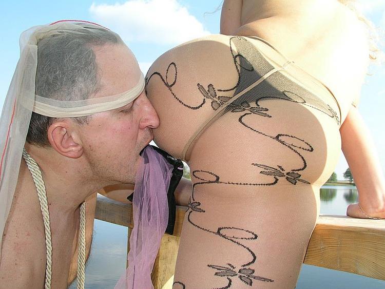 15P Une blonde seins nus est vénérée par un homme soumis sur un quai au bord d'un lac