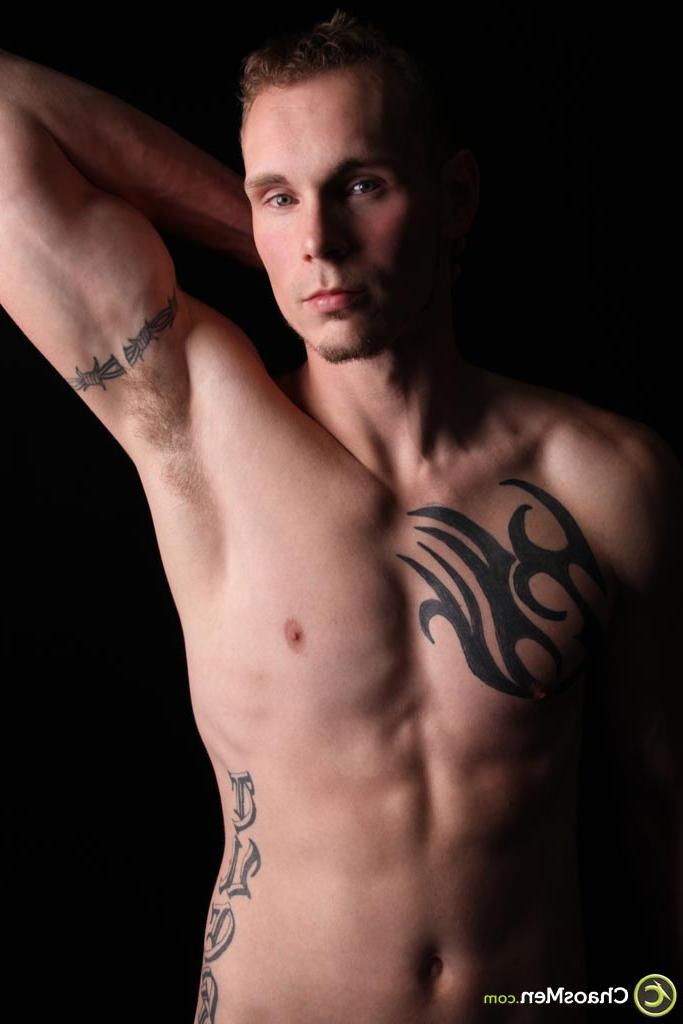 20P El modelo gay rubio Kirk muestra su cuerpo tatuado y se masajea la polla en el sofá