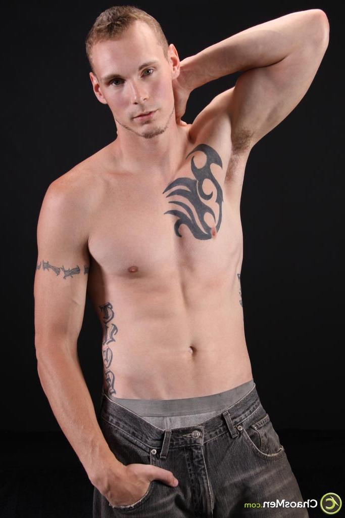 20P El modelo gay rubio Kirk muestra su cuerpo tatuado y se masajea la polla en el sofá