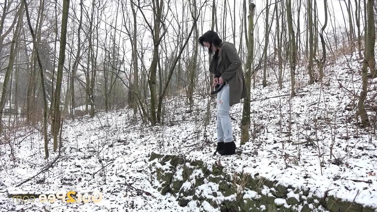 15P La brune Selena pisse sur un sol enneigé dans les bois.
