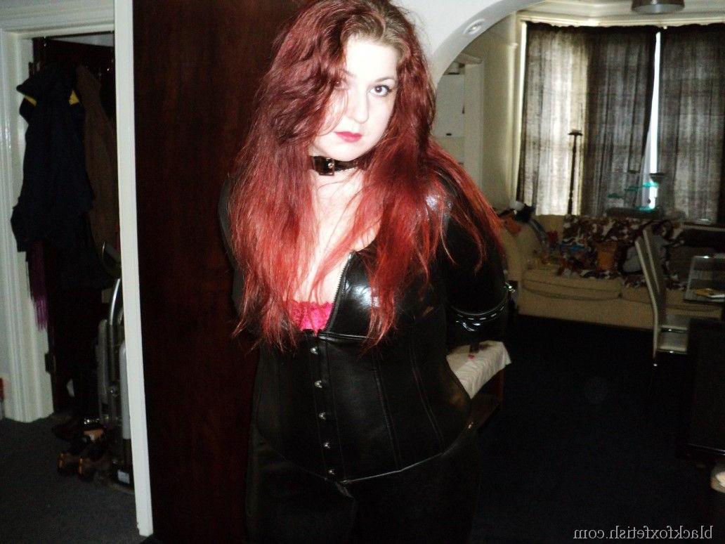 16P Redheaded slave is fitted with a hood and ball gag in black latex clothing