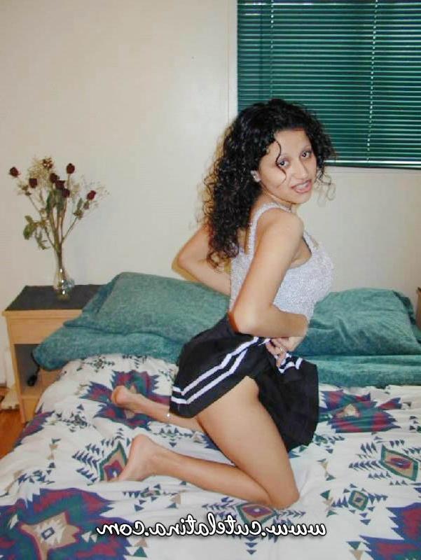 15P Une jolie fille latina découvre ses seins naturels en s'agenouillant sur un lit.