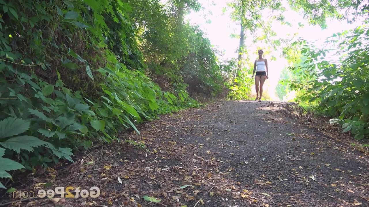 15P La chica bajita Ali Bordeaux hace pis mientras camina por un sendero en el bosque
