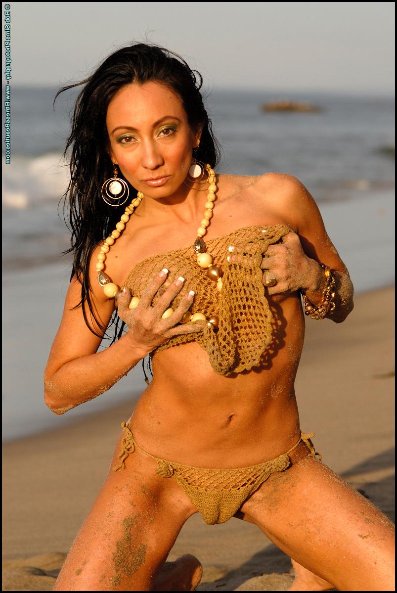 15P Bodybuilder Monica Goe poses on a beach in see-through swimwear