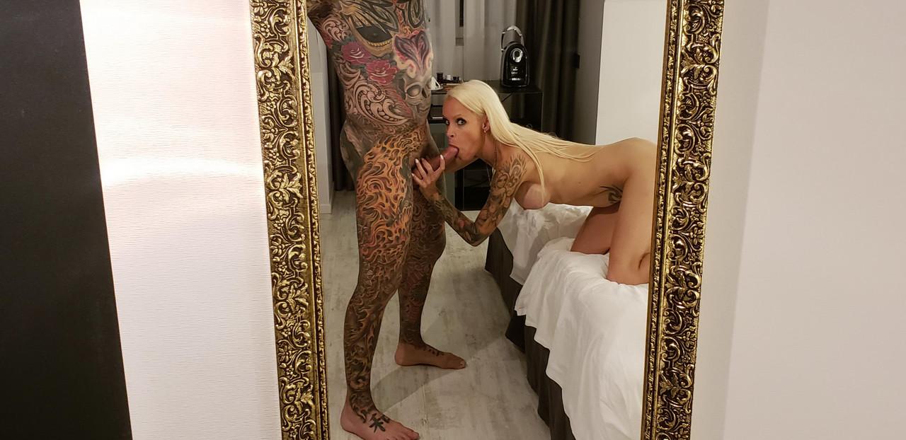 16P Une blonde nue fait une pipe en POV à un homme fortement tatoué sur un lit