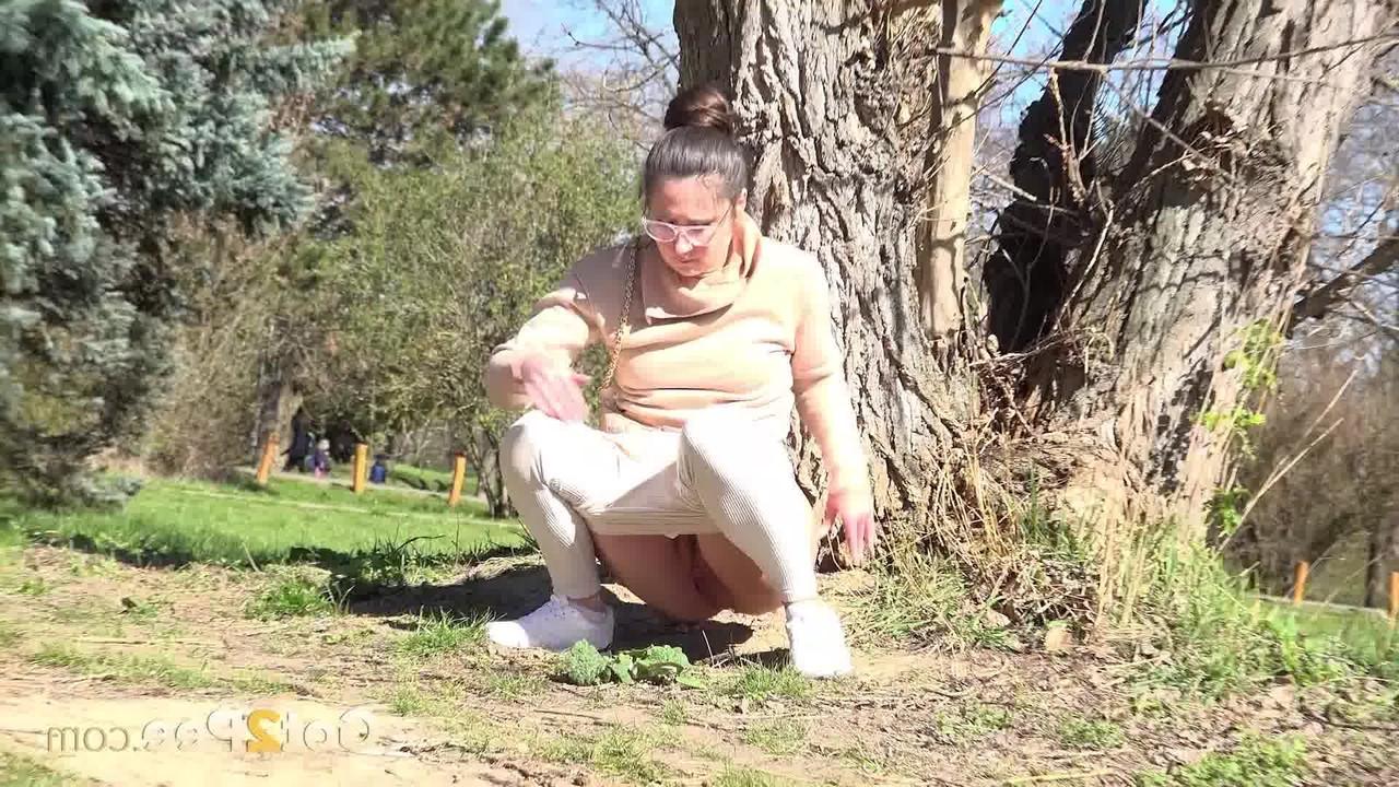 14P La chica caucásica Lara Fox se recuesta contra un árbol mientras orina