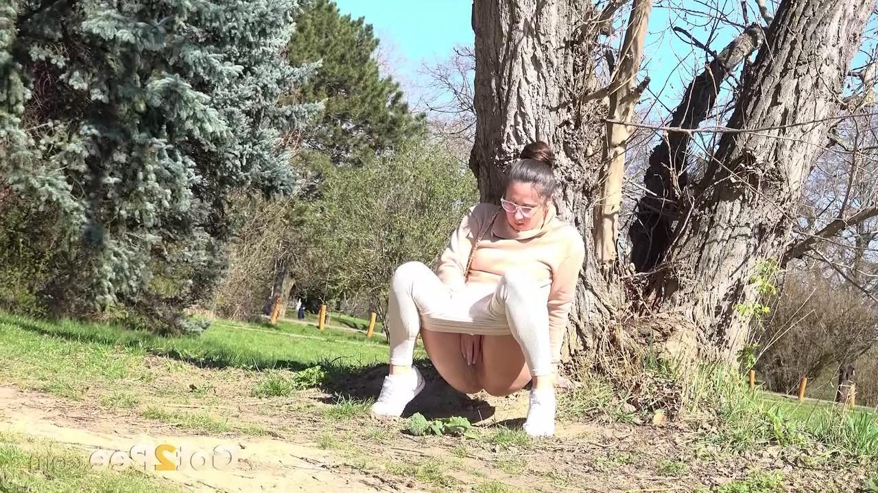 14P La chica caucásica Lara Fox se recuesta contra un árbol mientras orina