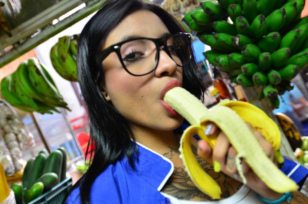 15P Une Latina tatouée tentante mange et lèche une banane de manière provocante en public