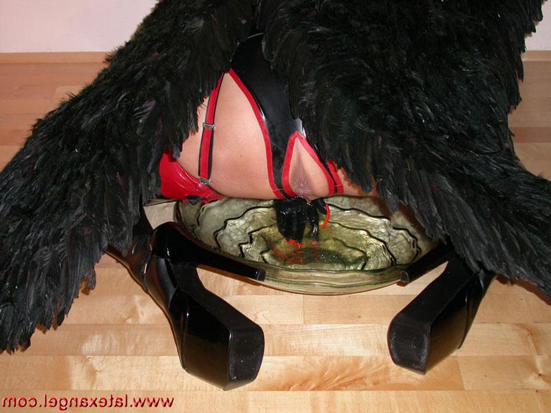 15P Redhead chick pees into a glass bowl while wearing angel wings and latex wear