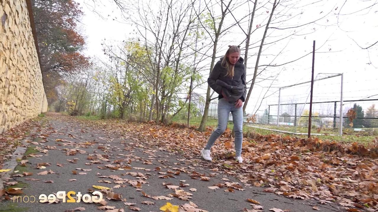 15P A branca Claudia Macc mija nas folhas caídas perto de um parque esportivo