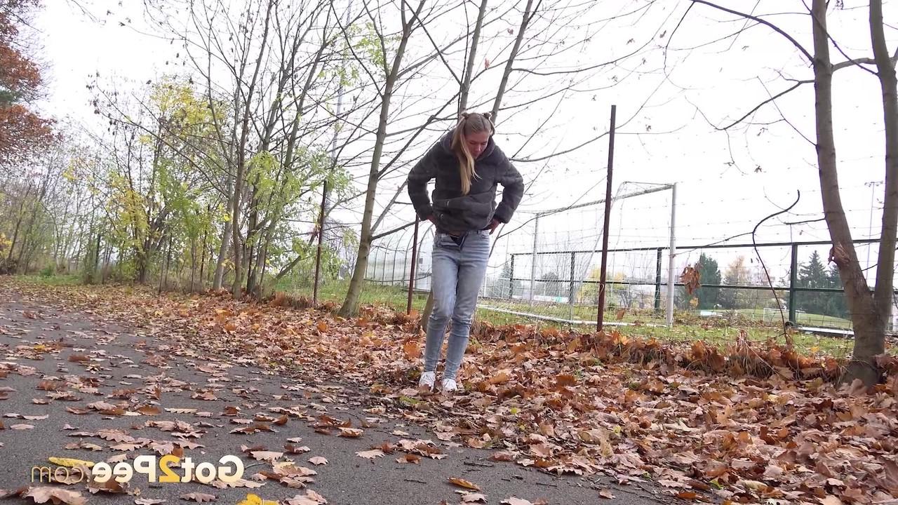 15P A branca Claudia Macc mija nas folhas caídas perto de um parque esportivo