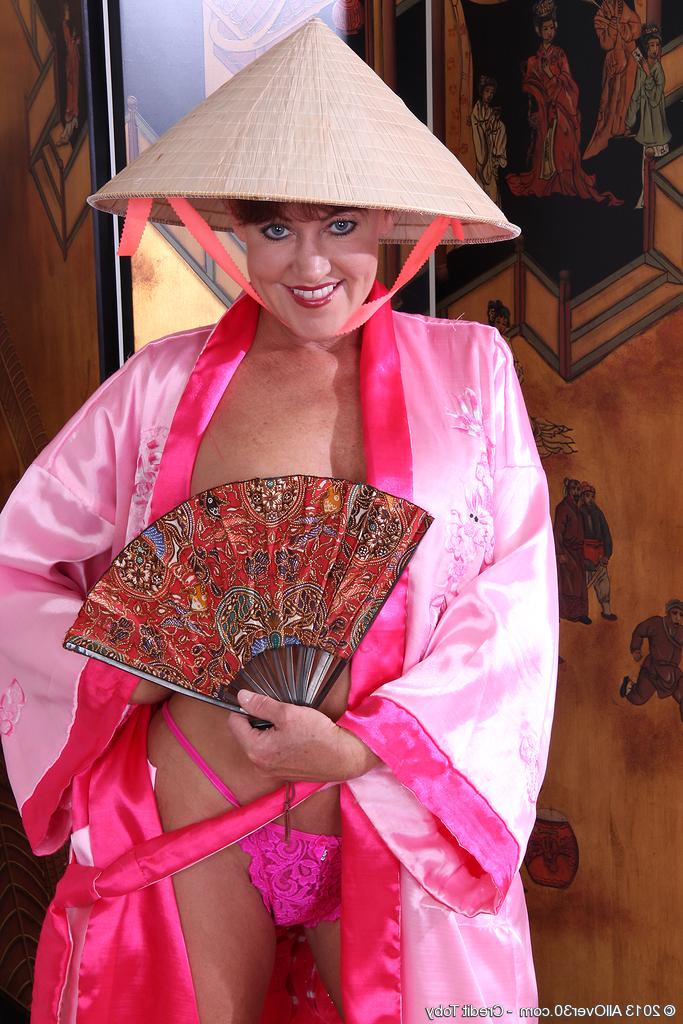16P Mulher madura Shauna fica com sapatos pretos diante de uma tela oriental