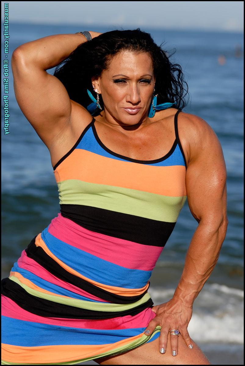 15P Die brünette Bodybuilderin Tonia Moore lässt in einem Kleid am Strand ihre Muskeln spielen
