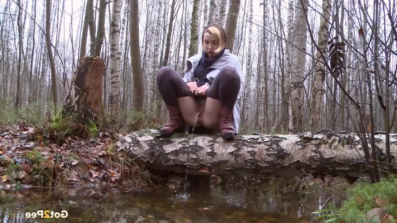 15P Clothed girl Anya pulls down tights on a log to pee into a stream in the woods