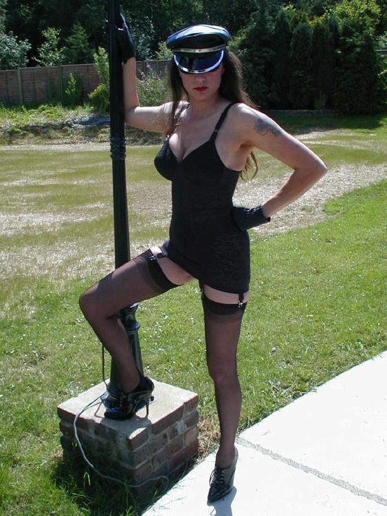 15P Nylon Jane models against a light stand in lingerie and a fetish themed cap