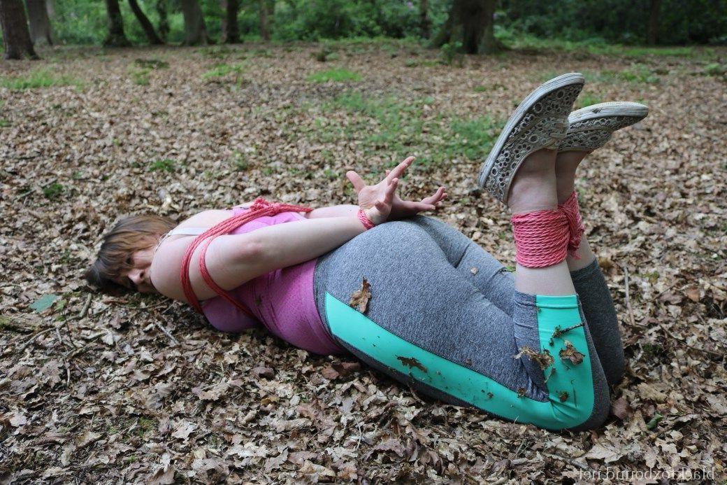 16P Caucasian girl is hogtied and gagged in her clothes upon dried leaves