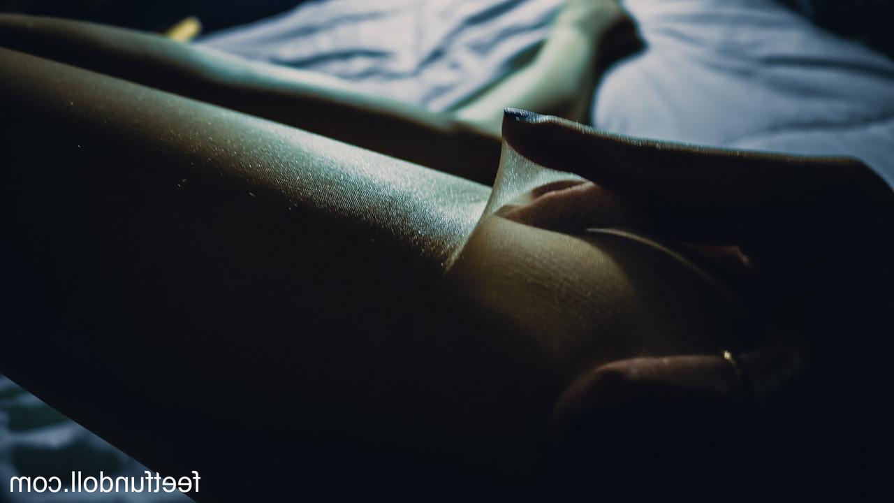 15P Lisa Dove, une jeune femme nue, montre ses jambes sexy et sa chatte taillée sur son lit.
