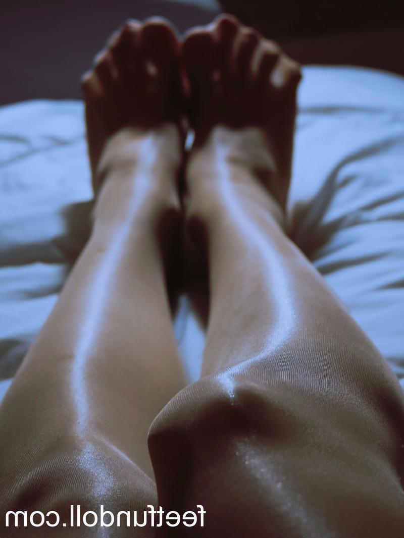 15P Lisa Dove, une jeune femme nue, montre ses jambes sexy et sa chatte taillée sur son lit.